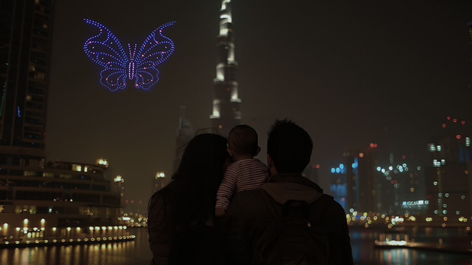 Family watching a drone light show in Dubai at night